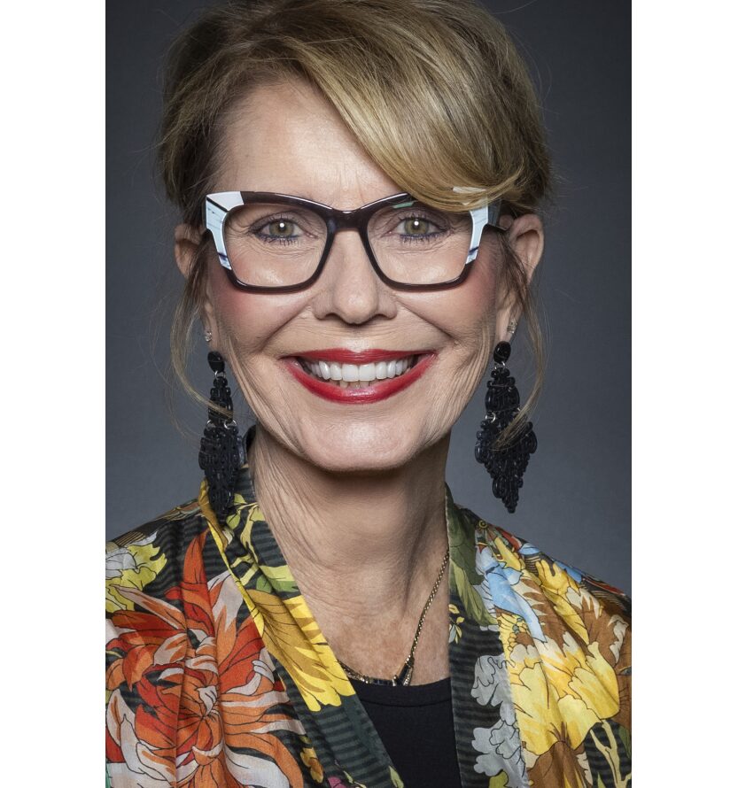 A woman with glasses and a floral jacket.
